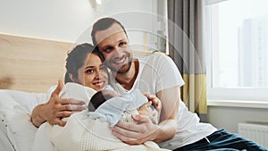 New mother and father in postnatal hospital department. Happy parents holding newborn baby boy in hospital ward. Smiling