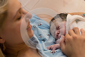New mother happily holding her newborn child moments after labor