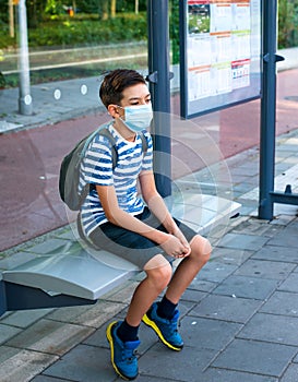 New normal Concept social distance, A boy wearing a medical face mask waiting at the Bus stop to go back to school. prevent pandem photo