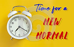 The new normal after COVID-19 Coronavirus pandemic concept. white alarm clock isolated on yellow with text time for a new normal