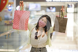 New normal habits - young attractive and happy Asian Chinese woman at shopping mall happy and excited enjoying sale in beauty