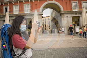 New normal holidays travel in Europe - young beautiful and happy Asian Chinese tourist woman with face mask and backpack taking