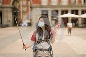New normal holidays travel in Europe - young happy and beautiful Asian Japanese tourist woman in face mask taking selfie with