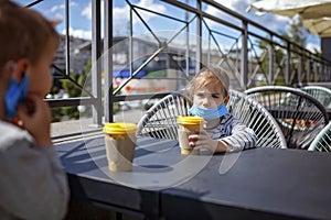 New normal reality, stay safe in street cafe, kids with medical mask waiting for breakfast