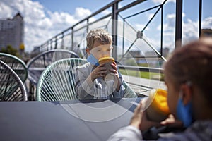 New normal reality, stay safe in street cafe, kids with medical mask waiting for breakfast