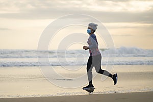 New normal running workout with face mask - attractive and happy middle aged woman on her 40s or 50s doing post quarantine jogging