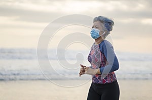 New normal running workout with face mask - attractive and happy middle aged woman on her 40s or 50s doing post quarantine jogging