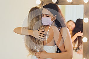 New normal. Two women together with medical protective facial facemask. Girls is hugging at the street. Coronavirus and