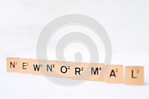 New normal word with selective focus on rustic plastic tiles alphabet puzzle board game. isolated on white background