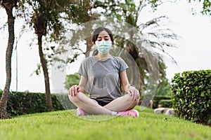 New normal, Young Asian woman wearing face mask and meditating in park