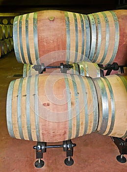 New oak wine barrels, filled with red wine, on metal support