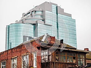 New office building of glass behind the destroyed brick house