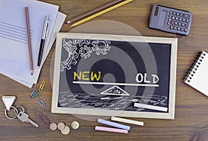 New and Old Balance. Chalkboard on wooden office desk