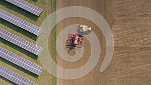 New and Old Farming as a Seed Drill Works Alongside a Solar Power Farm