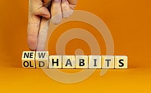 New or old habits symbol. Businessman turns wooden cubes and changes words `old habits` to `new habits`. Beautiful orange tabl