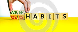 New or old habits symbol. Businessman turns wooden cubes and changes words `old habits` to `new habits`. Beautiful yellow tabl