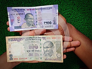 New and old Indian hundred rupees note placed in human hand.