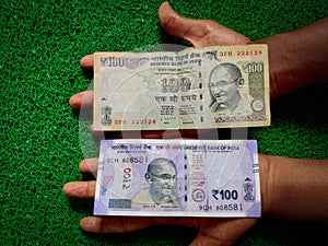 New and old Indian hundred rupees note placed in human hand.