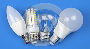 New and old light bulbs together, blue background. Energy saving concept. Flat lay, top view photo