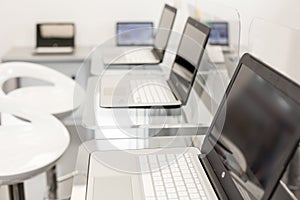 New, open laptops, on a glass desktop; modern white chairs in background photo
