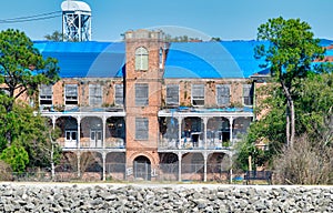 New Orleans, LA - February 11, 2016: A rustic abandoned warehouse on the shoreline as viewed on a boat while traveling along the