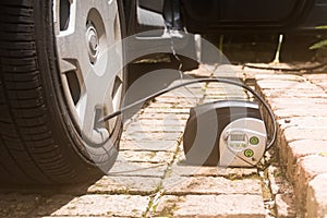 Portable air compressor pumping air into flat tire