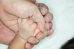 New parent holds his newborn infant baby`s hand for the first time. Parent holding newborns hand. Hand in hand. Parenthood. Mother