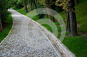 A new park path made of irregular cubes, folded with a side channel for draining water from the road surface. granite stones of
