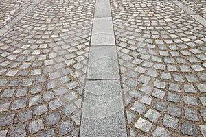New paving made with grey stone slabs and small stone cube blocks interlocked with sand in curved shape in a pedestrian zone
