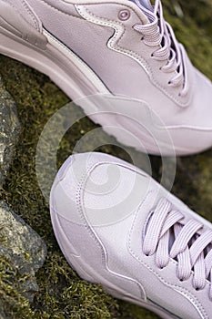 New pink sneakers on the background of stones. Running shoes - woman