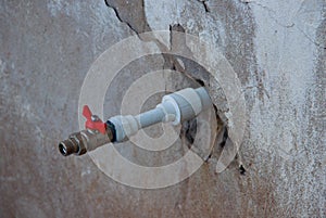 A new plastic pipe with the red faucet coming out of the old wall