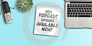 NEW PODCAST EPISODE AVAILABLE NOW on notepad on desk with microphone and laptop computer