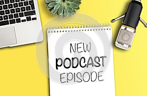 NEW PODCAST EPISODE on notepad on desk with microphone and laptop computer