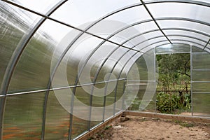 New polycarbonate greenhouse with metal frame in the garden in summer