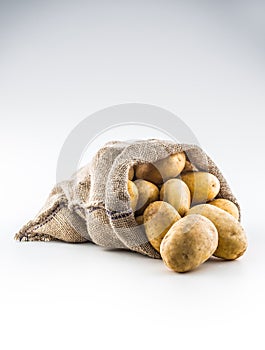 New potatoes in burlap sack isolated on white.