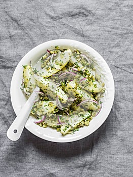 New potatoes, gherkins, red onions, french mustard olive oil dressing salad on a grey background, top view