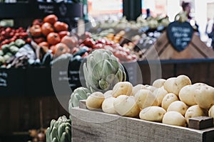 New potatoes on sale at a market stall, fruits and vegetables on the background