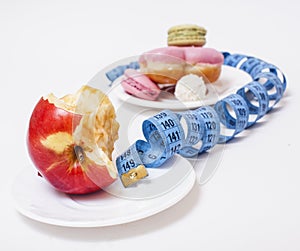 new real diet concept, question sign in shape of measurment tape between red apple and donut isolated on white