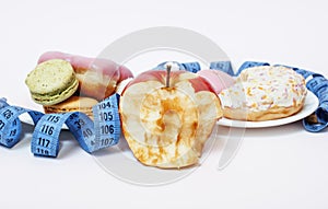 New real diet concept, question sign in shape of measurment tape between red apple and donut isolated on white close up