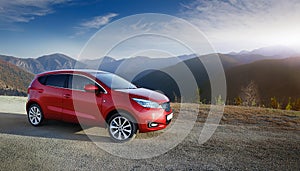 A new red car pulled over on the side of a remote mountain road
