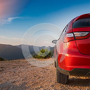 A new red car pulled over on the side of a remote mountain road
