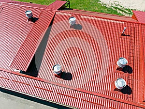 New red metal warehouse roof with installed pipes of ventilation