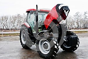 New red tractor with open motor at snowy weather
