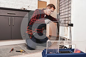 New refrigerator installation. Senior male technician checking refrigerator