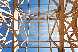 New residential wooden construction home framing against a blue sky.