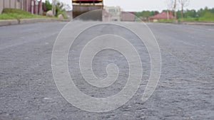 New road pavement, asphalt paving machine in the blurred background.