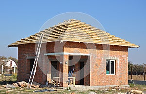 New Roof Membrane Coverings Wooden Construction Home Framing with Roof Rafters and Metal Ladder Outdoor against a Blue Sky.