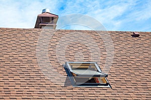 New roof with skylight, asphalt roofing shingles and chimney. Roof with mansard windows