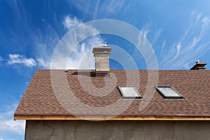 New roof with skylight, asphalt roofing shingles and chimney. Roof with mansard windows