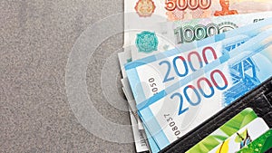 New Russian banknotes in denominations of 1000, 2000 and 5000 rubles and credit cards in a black leather purse close-up